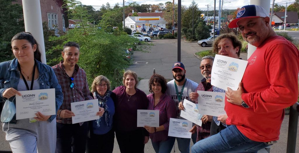 group of people standing on stairs holding certificates with parking lot in the background